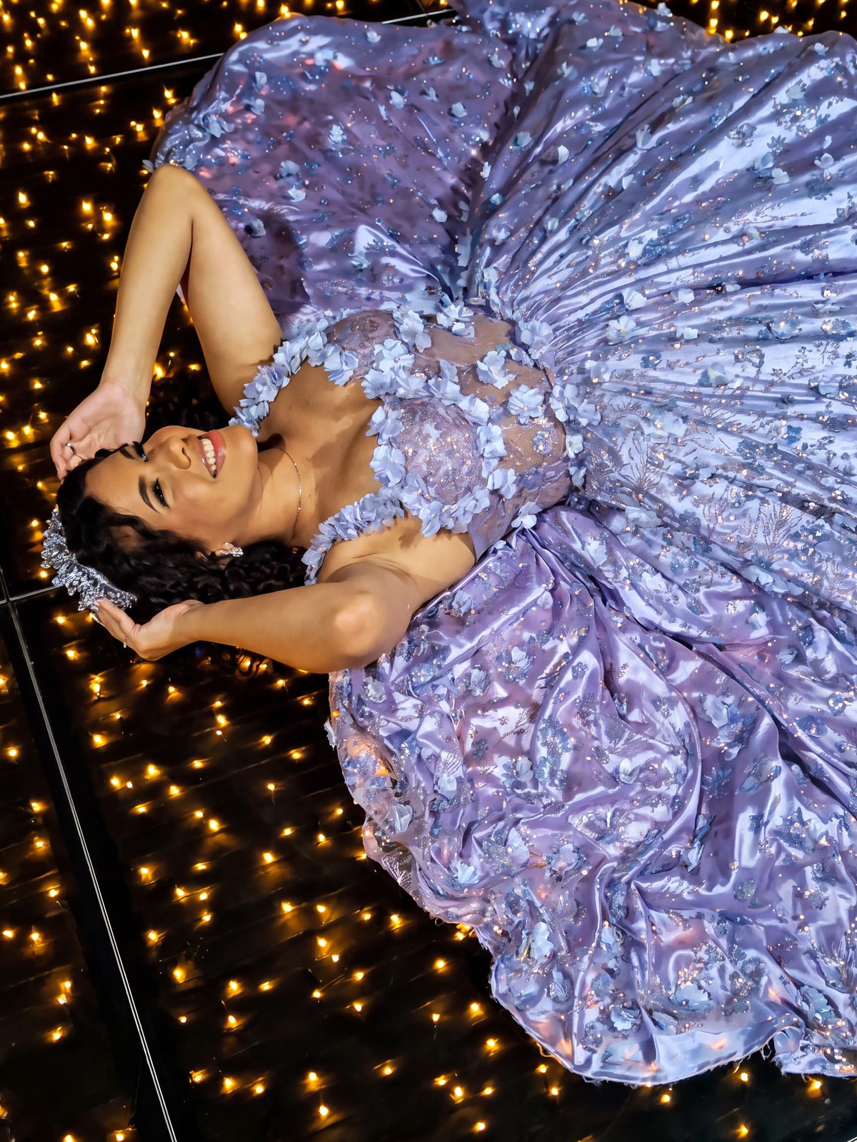 Debutante sobre um tapete de luzes, com o vestido espalhado